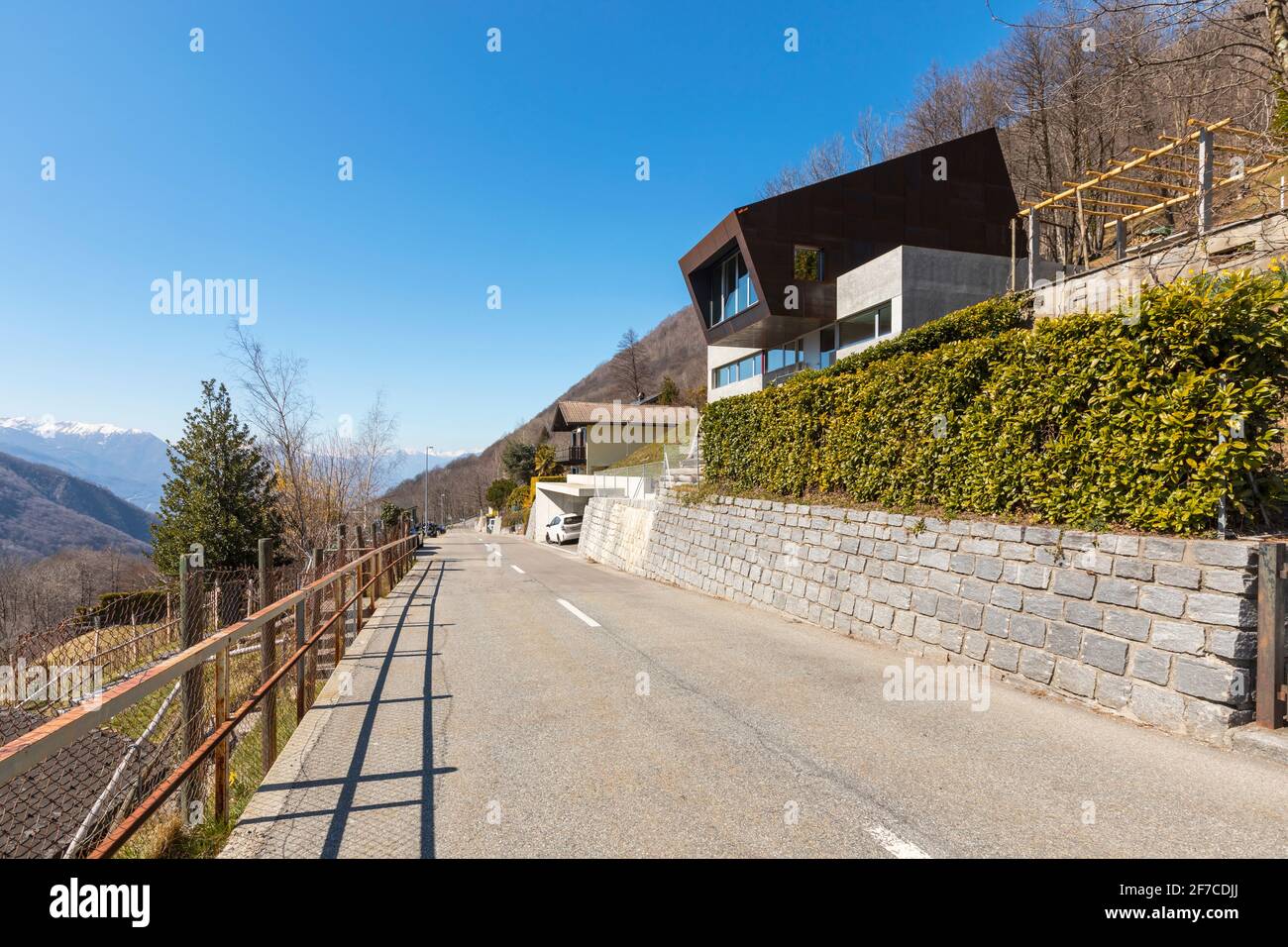 Esterno moderna villa isolata, circondata dalla natura. Rivestimenti in ferro e calcestruzzo. Strada anteriore deserta. Nessuno dentro Foto Stock
