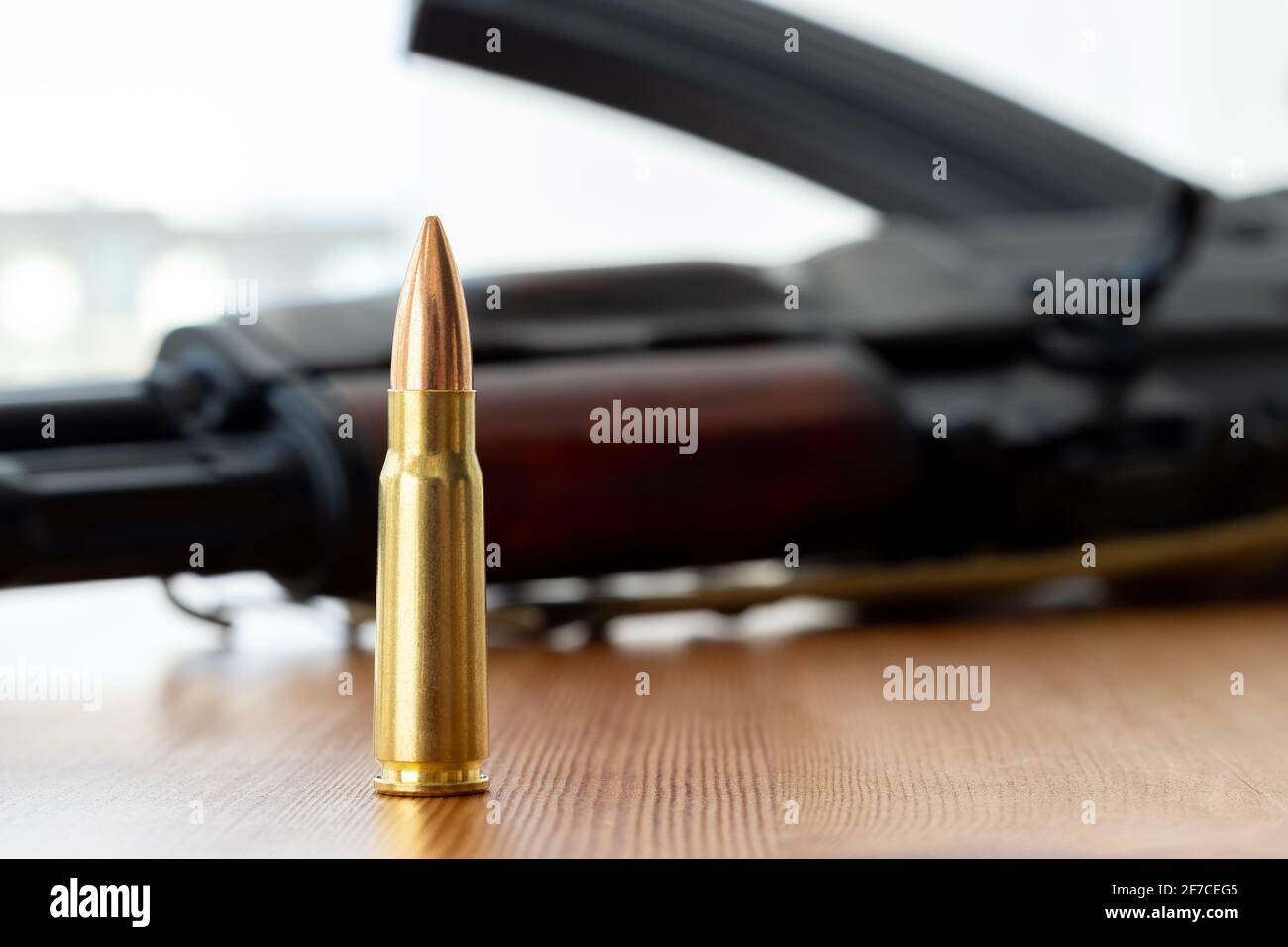 Un proiettile contro lo sfondo sfocato del fucile d'assalto Kalashnikov. Calibro cartuccia 7.62 per il closeup ak 47. Foto Stock