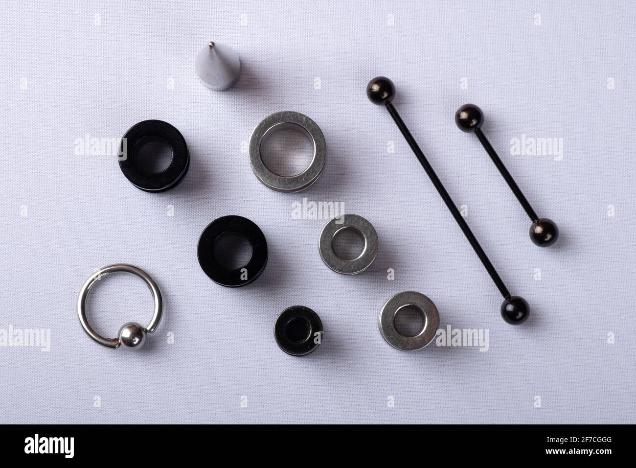 gioielli auricolari, tunnel auricolari in nero e argento con dilatatore e  piercing impilati su sfondo bianco vista dall'alto Foto stock - Alamy