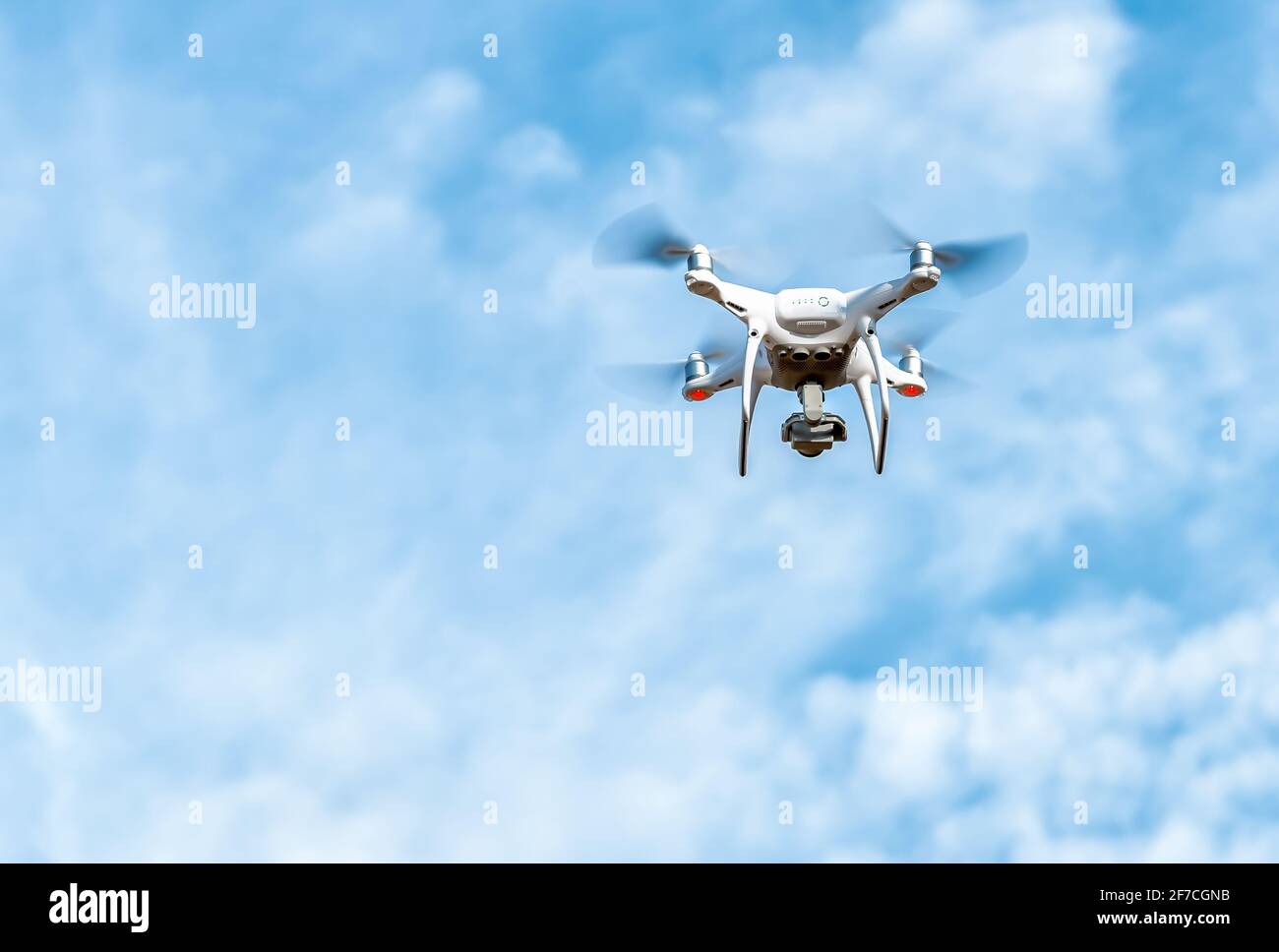 Drone bianco che vola in un cielo blu nuvoloso. Foto Stock