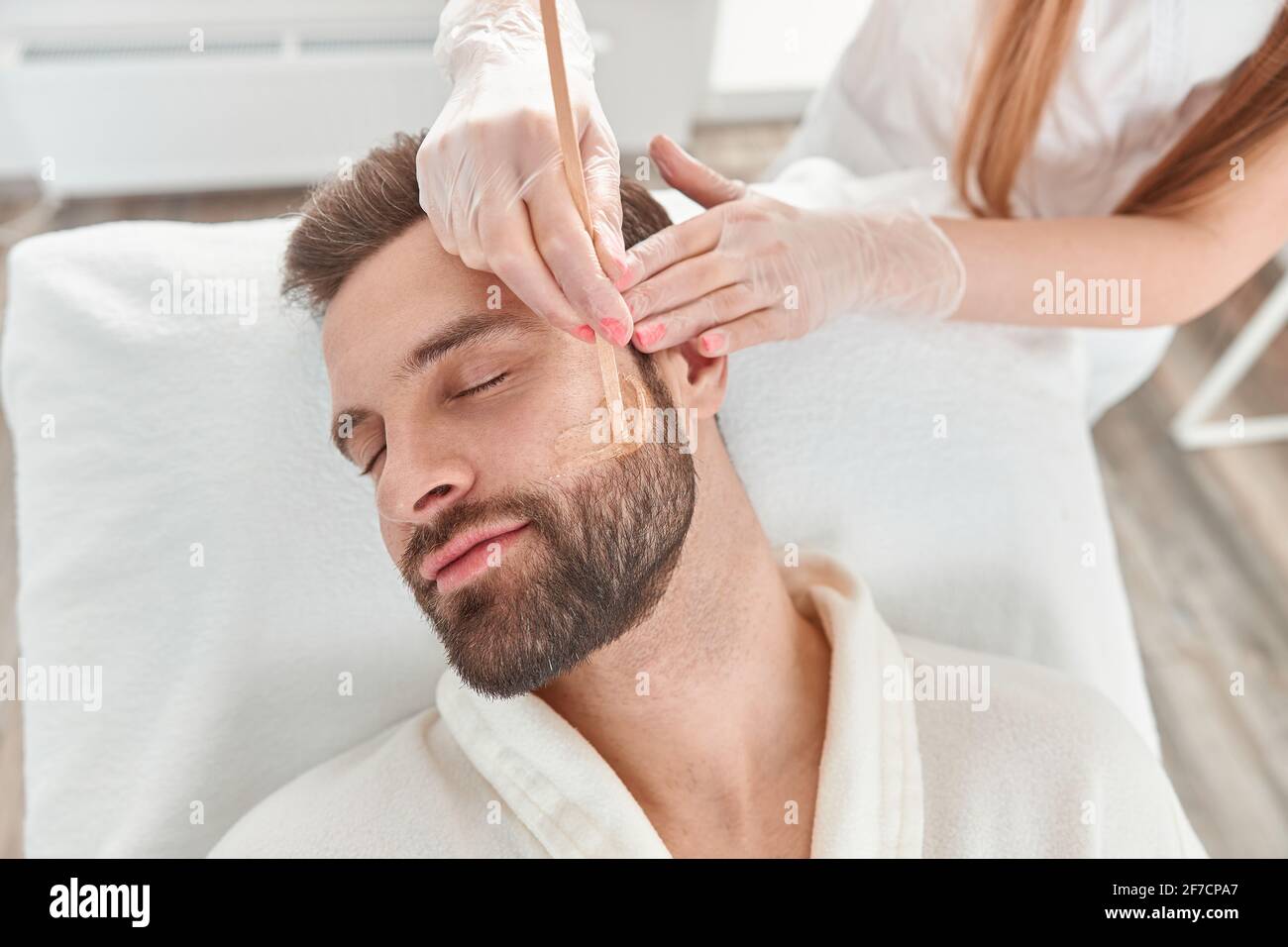 Concetto di cosmetologia e facciale. Una beautician donna fa il viso e la  barba modellando per un uomo che ceretta epilazione. Depilazione con cera  Foto stock - Alamy