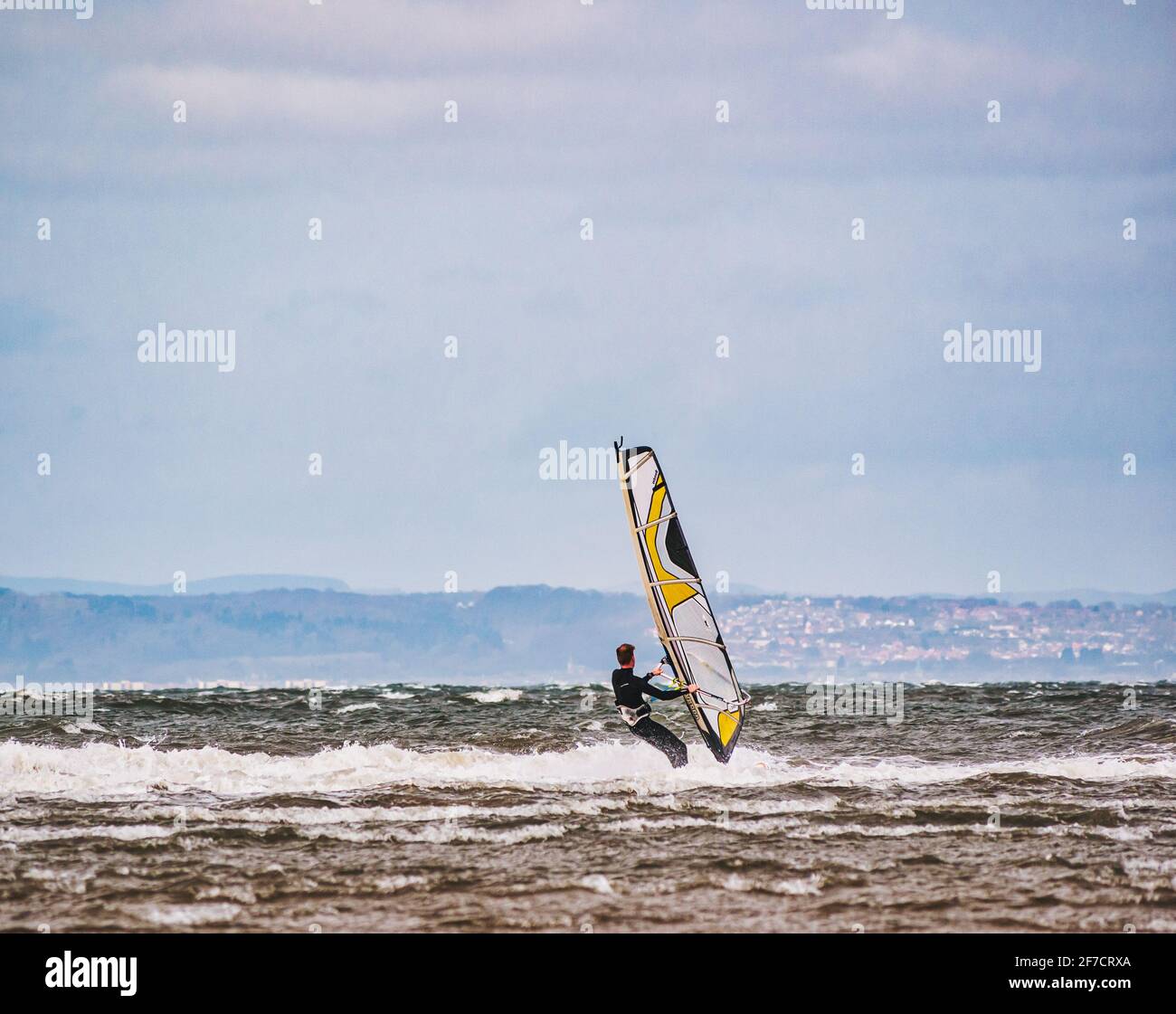 Uomo windsurf a Longniddry Bents in giornata ventosa in mare agitato, Firth of Forth, Scozia, Regno Unito Foto Stock