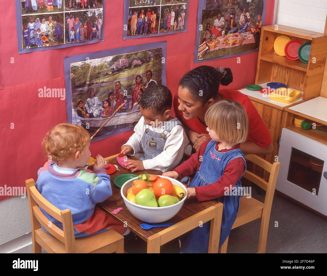 Bambini in asilo con assistente di stanza dei bambini, Surrey, Inghilterra, Regno Unito Foto Stock