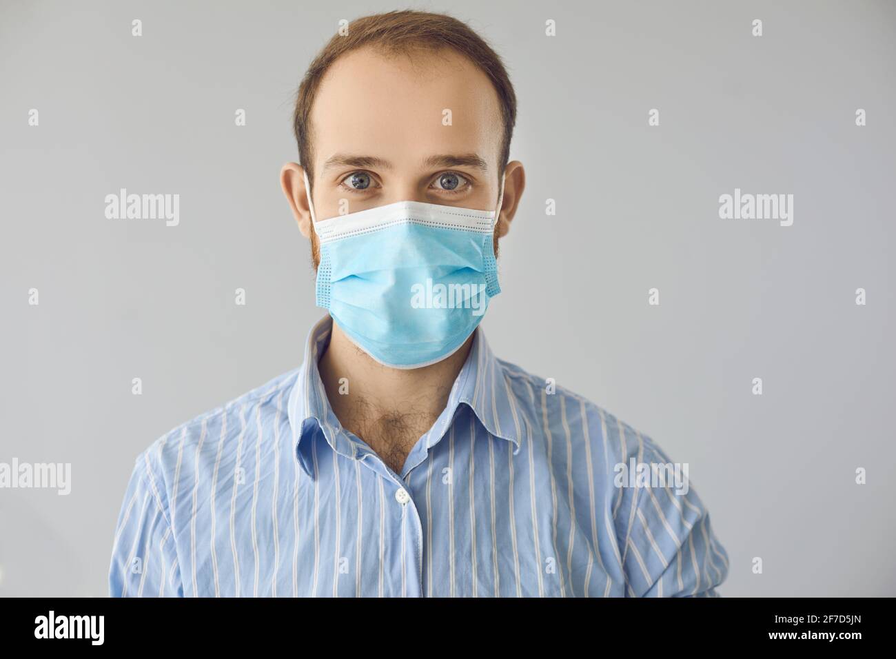 Ritratto di felice lavoratore di ufficio amichevole in faccia medica blu maschera che guarda la fotocamera Foto Stock