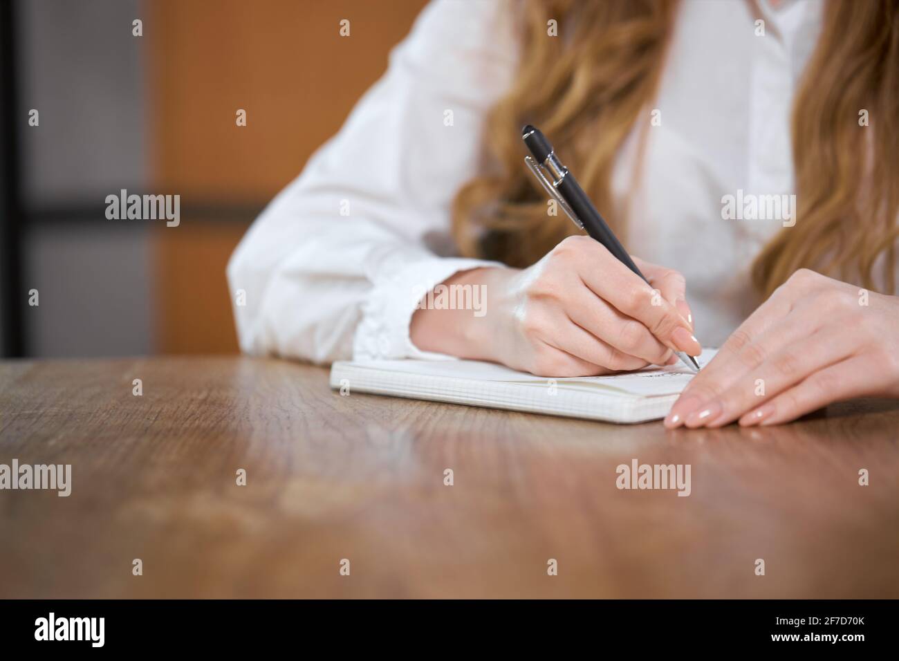 Primo piano di mano giovane donna che tiene la penna e scrivere diverse informazioni interessanti. Concetto di processo di scrittura di informazioni importanti per i seguaci o per voi stessi. Foto Stock