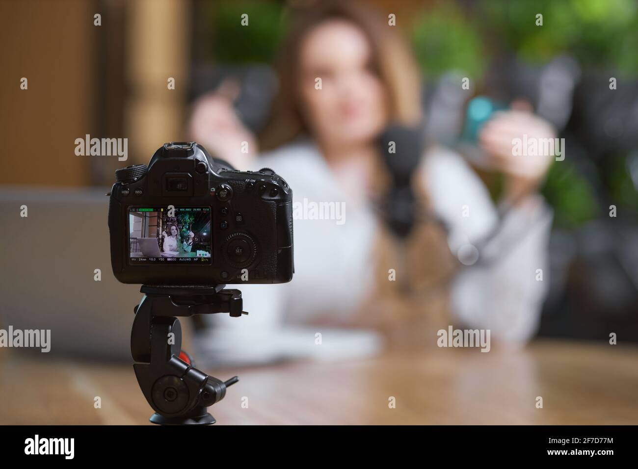 Primo piano di una moderna telecamera nera registrazione intervista o nuova video donna blogger in caffetteria. Concetto di processo comunicazione video blogger con seguaci online. Foto Stock