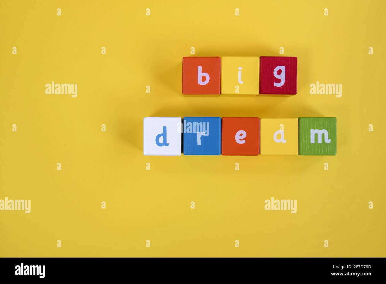 Parole Big Dream fatto da blocchi di legno colorati. Sono disposte in due file. Cubi dipinti con lettere su sfondo giallo. Vista dall'alto Foto Stock