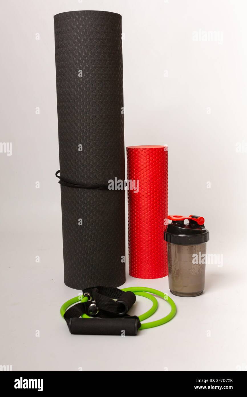 Una selezione di attrezzature per esercizi. Un tappetino yoga, un frullato proteico, un rullo posteriore e bande di resistenza. Esercizio fisico, vita sana, concetto di mantenersi in forma Foto Stock
