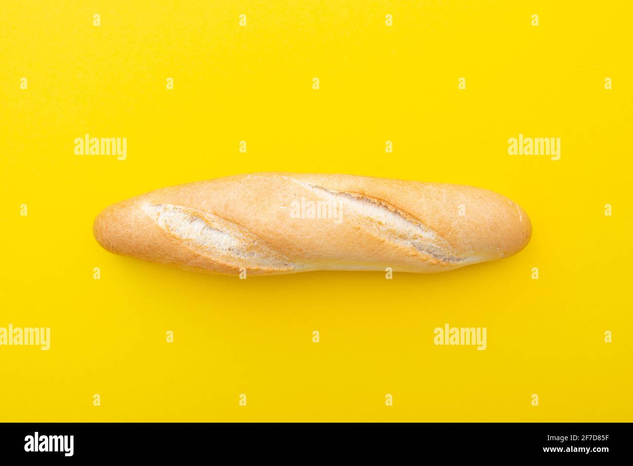 Baguette, pane francese, pane su sfondo giallo come layout. Piccolo pane francese, vista dall'alto, immagine creativa. Foto Stock
