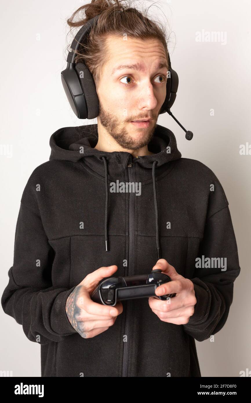 Giovane uomo con una cuffia per giochi e un controller che si concentra su un videogioco. E-sport, videogiochi, concetto di streaming Foto Stock