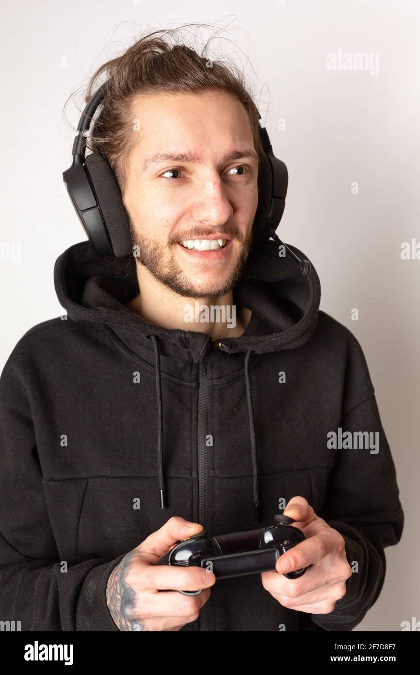 Giovane uomo con una cuffia per giochi e controller che si diverte a giocare un videogioco. E-sport, videogiochi, concetto di streaming Foto Stock