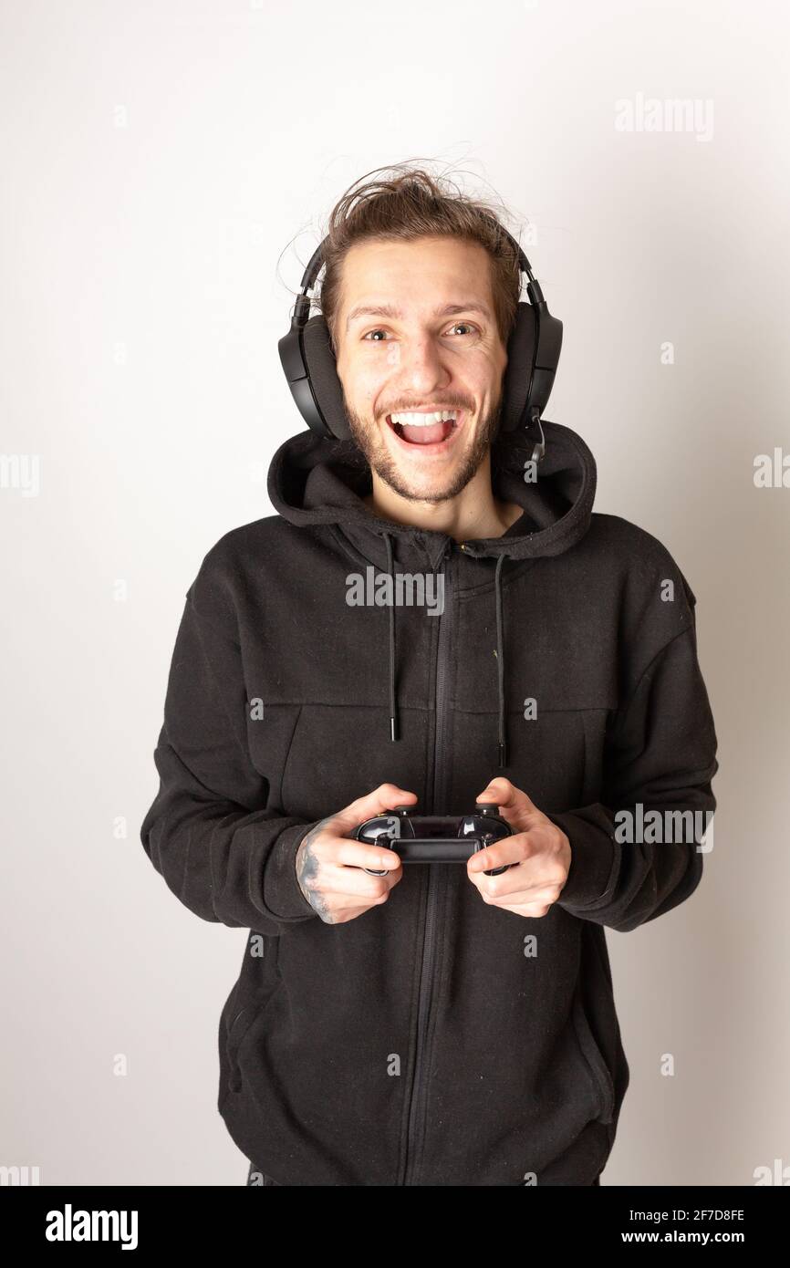 Giovane uomo con una cuffia per giochi e controller che si diverte a giocare un videogioco. E-sport, videogiochi, concetto di streaming Foto Stock