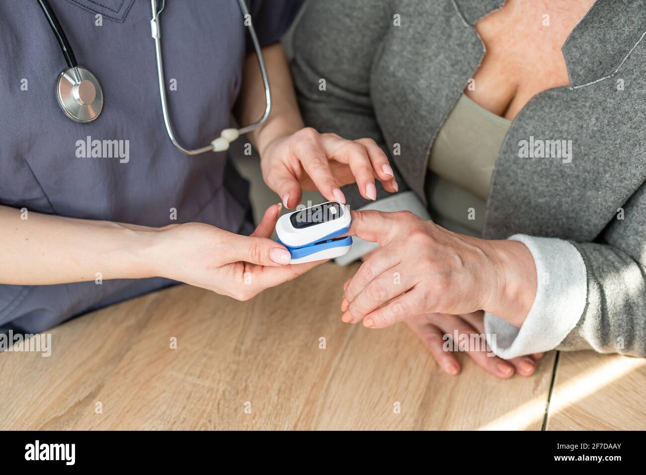 Medico che misura il livello di emoglobina del paziente. Mostra l'utilizzo del pulsossimetro per dito Foto Stock