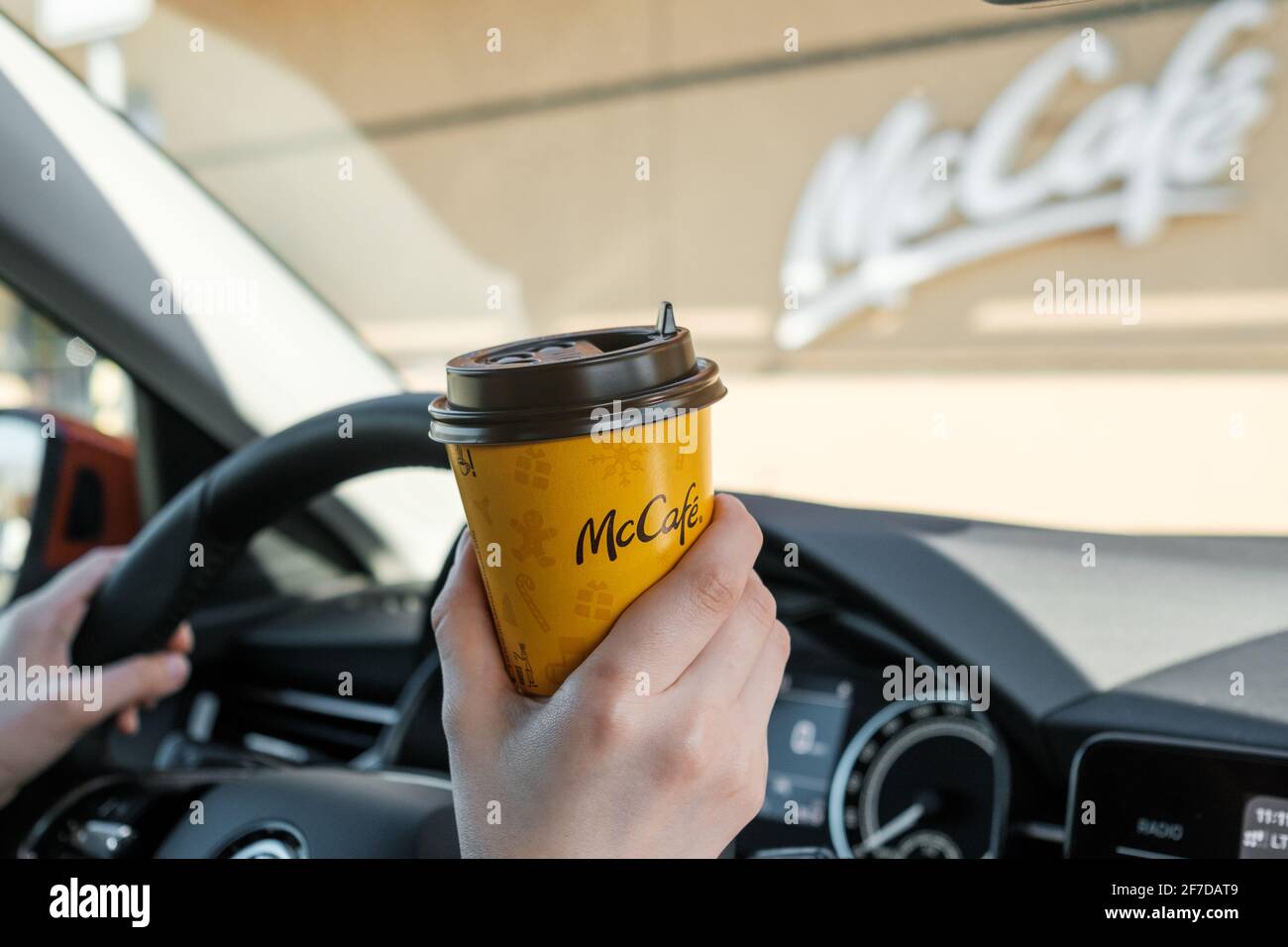Donna seduta in macchina e bevendo caffè da McCafe, aprile 2021, Praga, Repubblica Ceca. Foto Stock