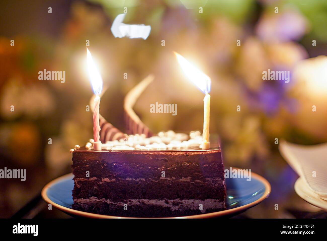 colpo di torta con candele scintillanti con fiamme e scintille che volano  con uno sfondo fuori fuoco di fiori, luci che mostrano un compleanno Foto  stock - Alamy