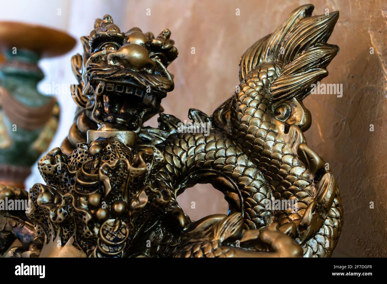 Primo piano di una scultura in drago d'oro, contro una parete d'oro in gesso veneziano, bokeh, febbraio 2021. Foto Stock