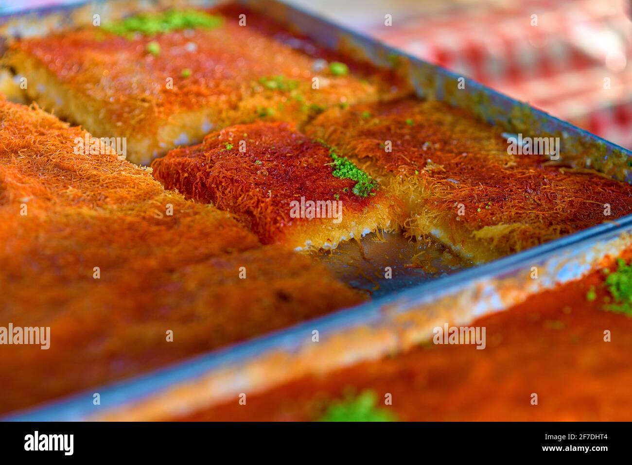 Dolce arabo dessert kunefe, kunafa, kadayif con polvere di pistacchio e formaggio sul vassoio nel Market.fuoco selettivo. Foto Stock