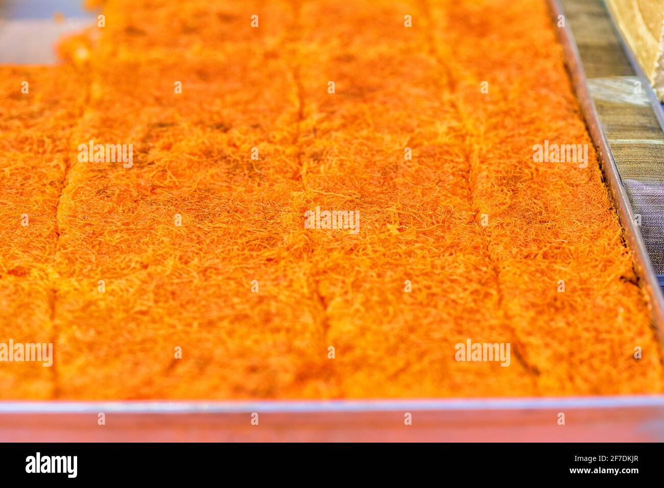 Dolce arabo dessert kunefe, kunafa, kadayif con polvere di pistacchio e formaggio sul vassoio nel Market.fuoco selettivo. Foto Stock