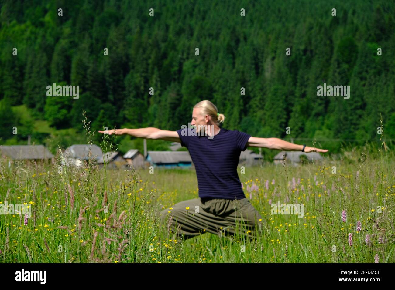 L'uomo che pratica esercizi di yoga in una giornata di sole nella foresta di montagne. Vacanze estive armonia all'aperto e vita sana. Oggetto principale sfocato Foto Stock