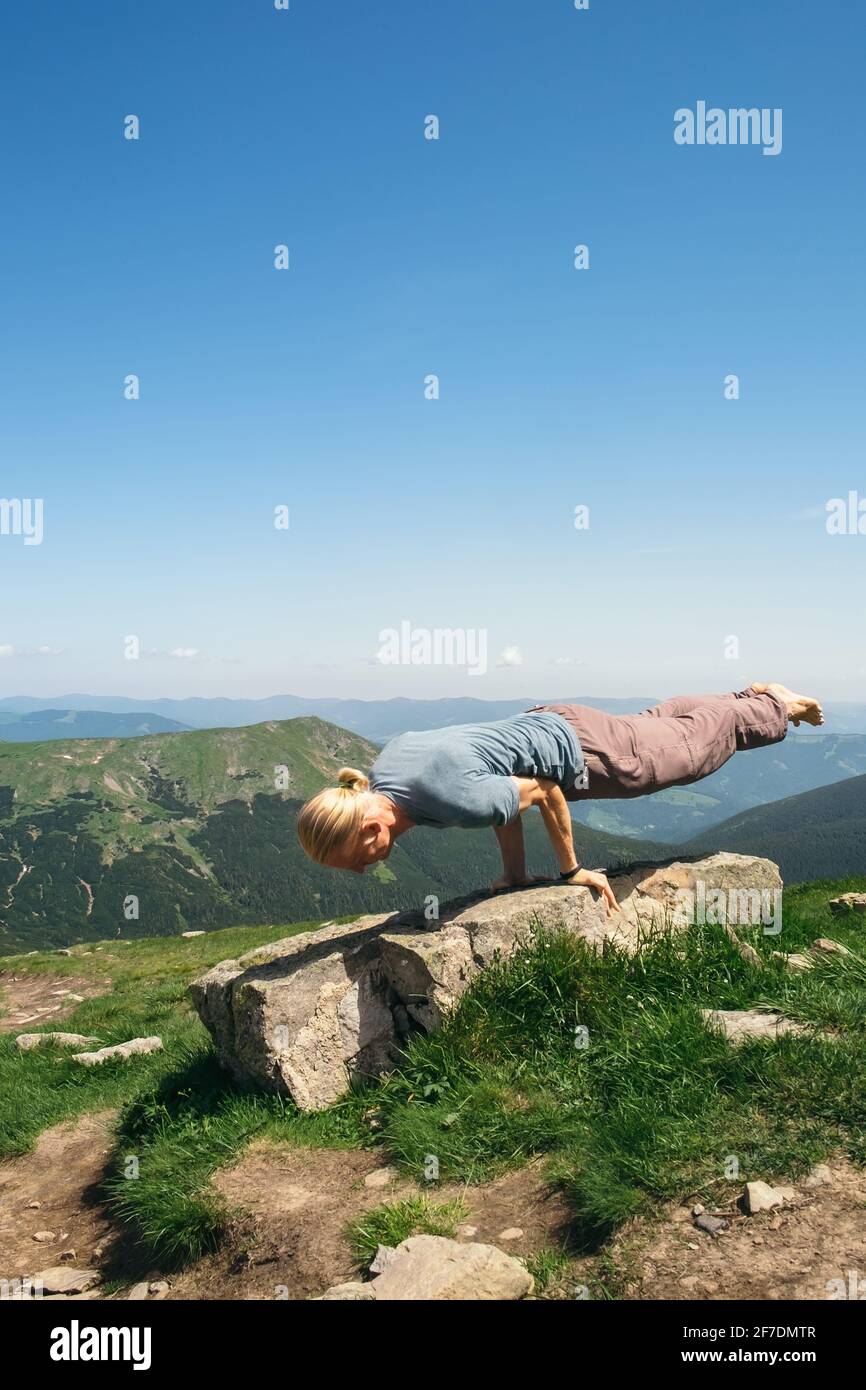 Uomo forte che pratica esercizi di yoga Balance in una giornata di sole sotto il cielo su una cima di montagna. Vacanze estive armonia all'aperto e vita sana Foto Stock