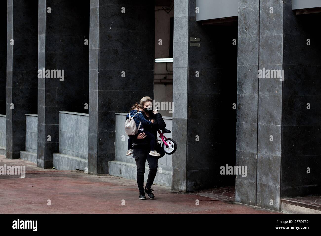 Giovane madre che porta la sua bambina assonnata e la sua bicicletta. Foto Stock