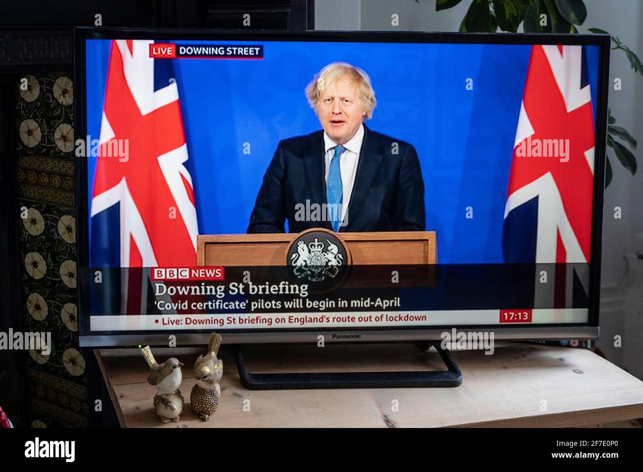 Briefing con Boris Johnson affiancato da Union Jacks nella nuova sala stampa di Downing Street. Testo ''certificato Covid' piloti da iniziare a metà aprile' Foto Stock