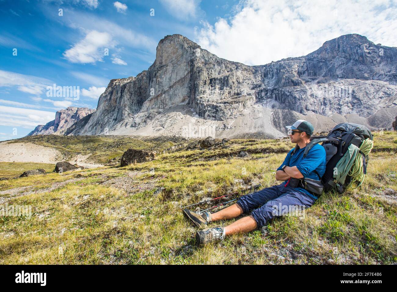 Backpacker riposo, seduto in prato erboso sotto la cima della montagna. Foto Stock