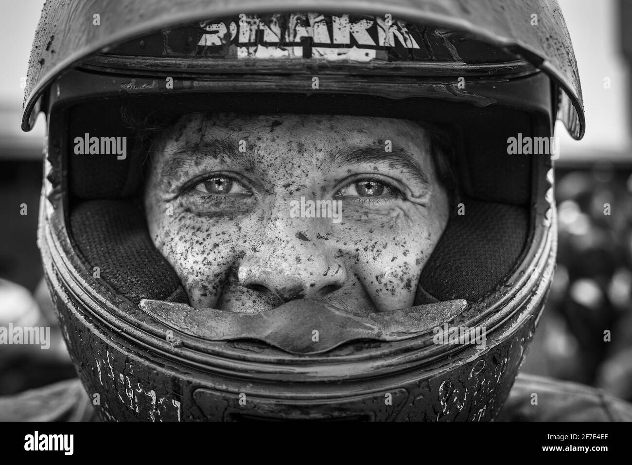 Primo piano di un uomo che indossa un timone coperto da fango.il volto di UN uomo coperto di punti fangosi dopo una sessione di moto. Foto Stock