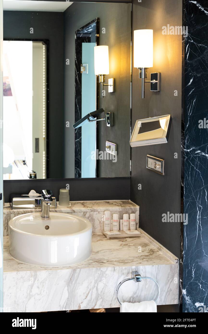 L'interno del bagno moderno in marmo blu e bianco, con lavabo bianco, grande specchio e accessori Foto Stock