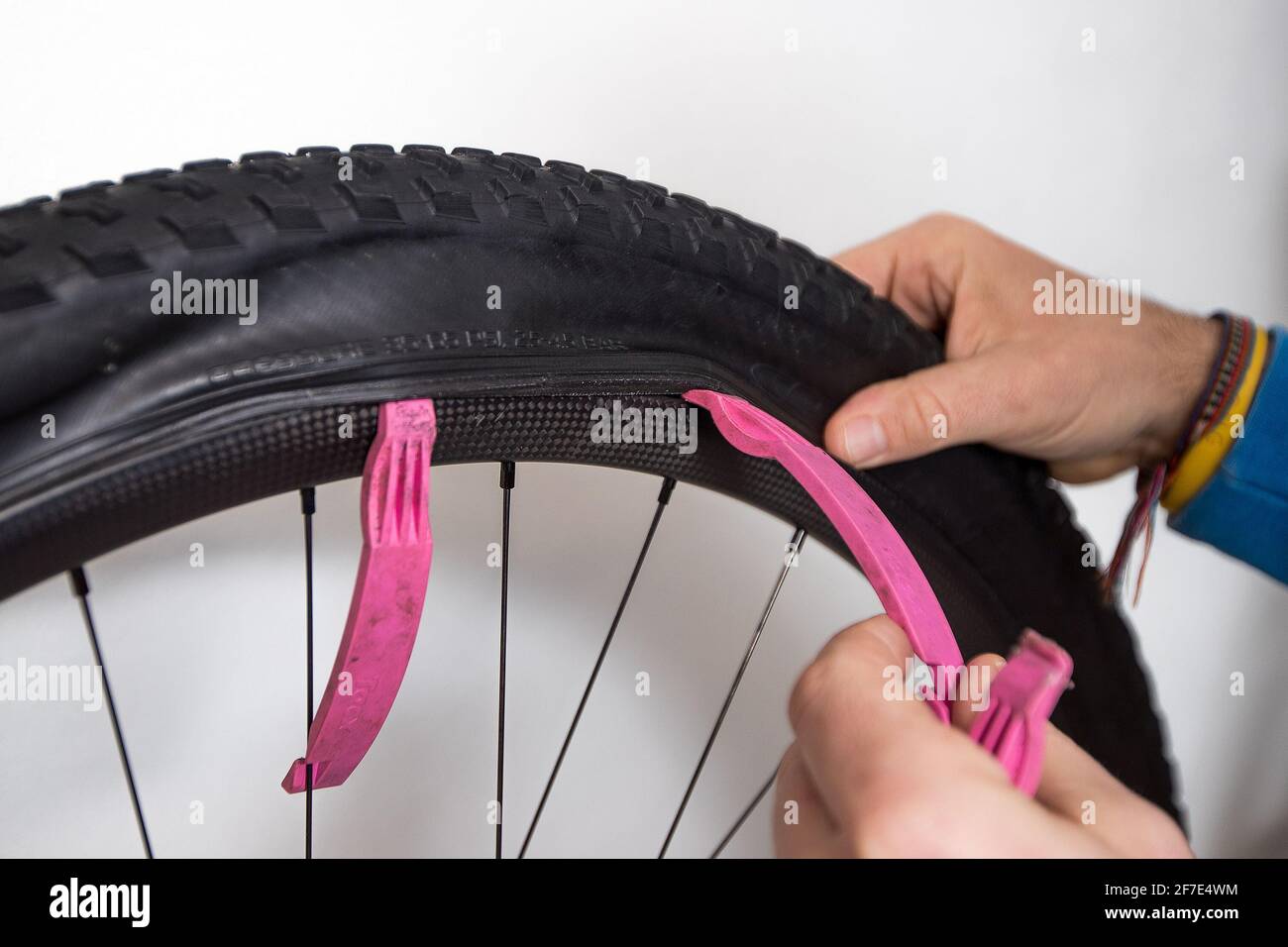 Riparazione del tubo della bicicletta. Una mano di una persona sta  rimuovendo uno pneumatico su una ruota di montagna di carbonio con un aiuto  delle leve rosa dello pneumatico Foto stock -