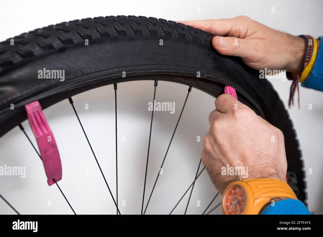 Riparazione del tubo della bicicletta. Una mano di una persona sta  rimuovendo uno pneumatico su una ruota di montagna di carbonio con un aiuto  delle leve rosa dello pneumatico Foto stock -