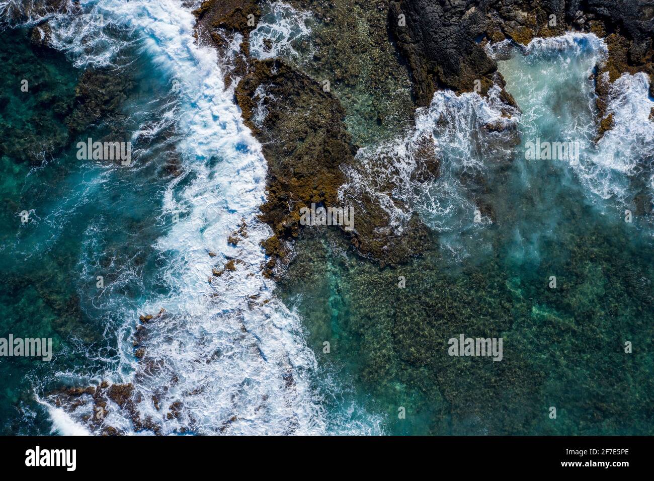 Drone foto di onde oceaniche che si infrangono su rocce marroni Hawaii Foto Stock