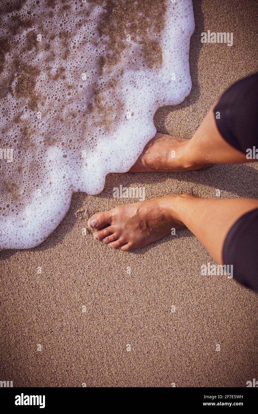 Schiuma di mare che si lava delicatamente sui piedi di un donna su un Giornata di sole alle Hawaii Foto Stock