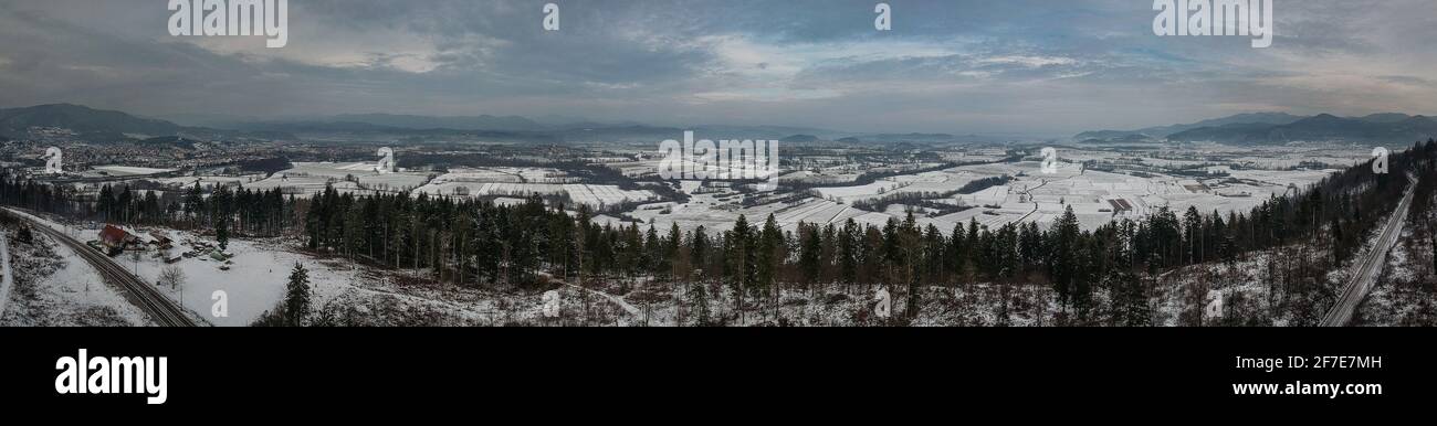 Panorama invernale su pianure bianche e campi delle paludi meridionali di lubiana e con nuvole, con montagne e fitte nuvole sullo sfondo. Immagine Foto Stock
