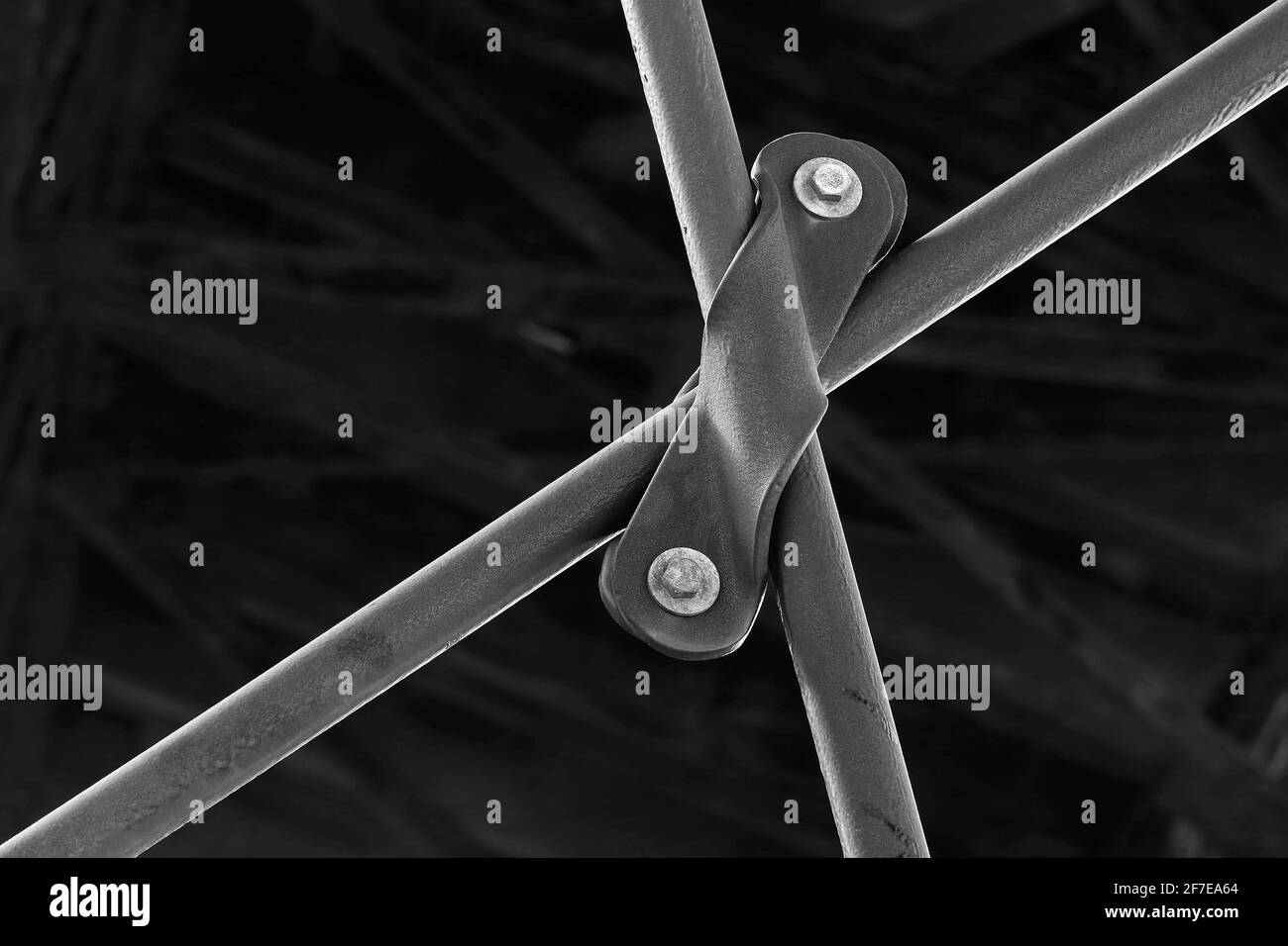 Primo piano immagine mono architettonica e astratta del morsetto strutturale sul lato inferiore del Queen's Pier Ramsey, Isle of Man formando una croce o "X" Foto Stock