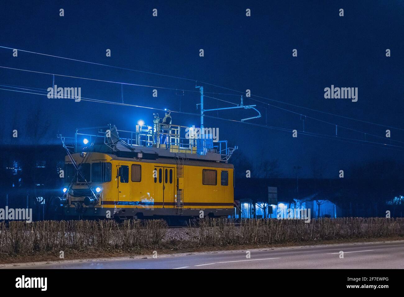 Treno di lavoro per la manutenzione della catenaria di notte. Lavoratori che lavorano di notte per consentire l'apertura della linea ferroviaria al mattino. Foto Stock