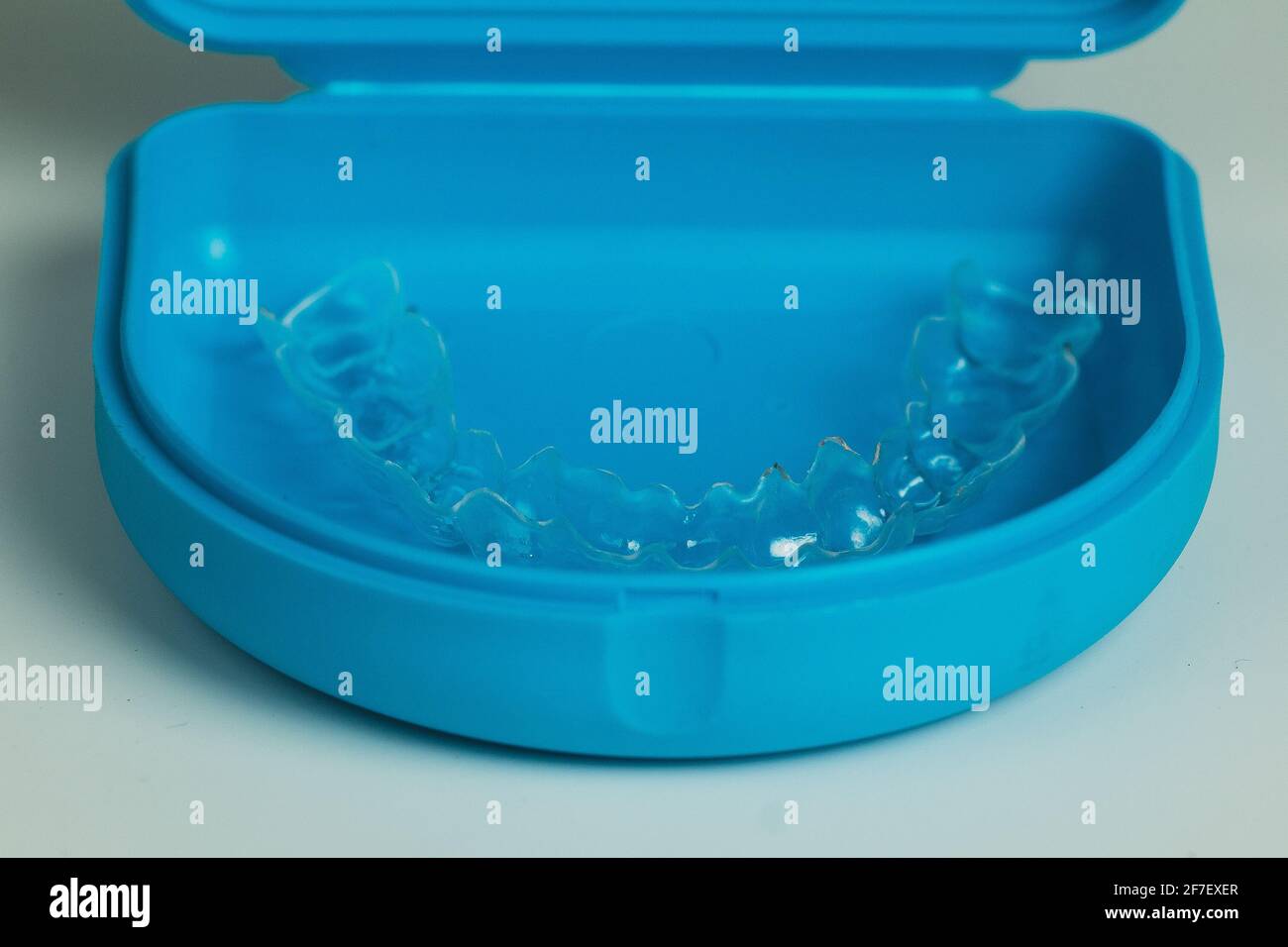 Fermo ortodontico realizzato in plastica trasparente in una custodia blu isolata in bianco. Fermo per l'allineamento dei denti. Foto Stock