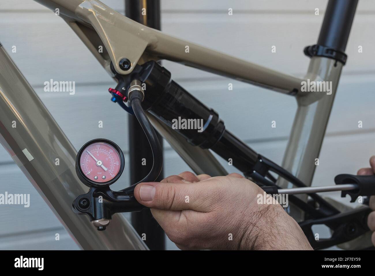 Pompare l'ammortizzatore o l'ammortizzatore posteriore di una moderna bicicletta di montagna utilizzando una pompa a pressione manuale. Regolazione della flessione in caso di urto pneumatico della bicicletta. Foto Stock