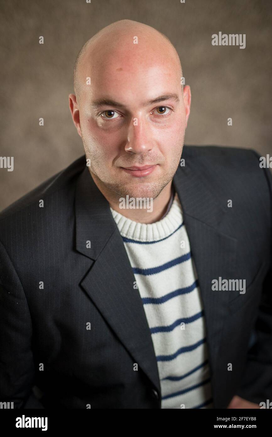 Ritratto di un moderno hipper business cripto uomo in un maglione a righe e un abito nero o giacca su sfondo grigio. Ritratto aziendale di giovani busi Foto Stock