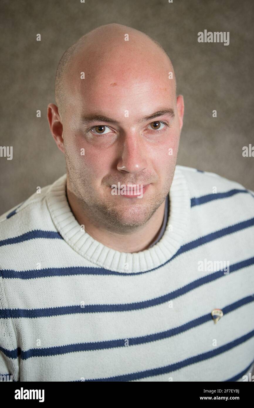 Ritratto di un moderno hipster hipster uomo cripto in un maglione a righe su sfondo grigio. Ritratto informale di giovane uomo d'affari Foto Stock