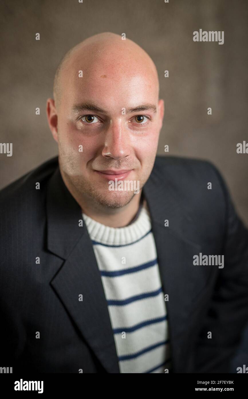 Ritratto di un moderno hipper business cripto uomo in un maglione a righe e un abito nero o giacca su sfondo grigio. Ritratto aziendale di giovani busi Foto Stock