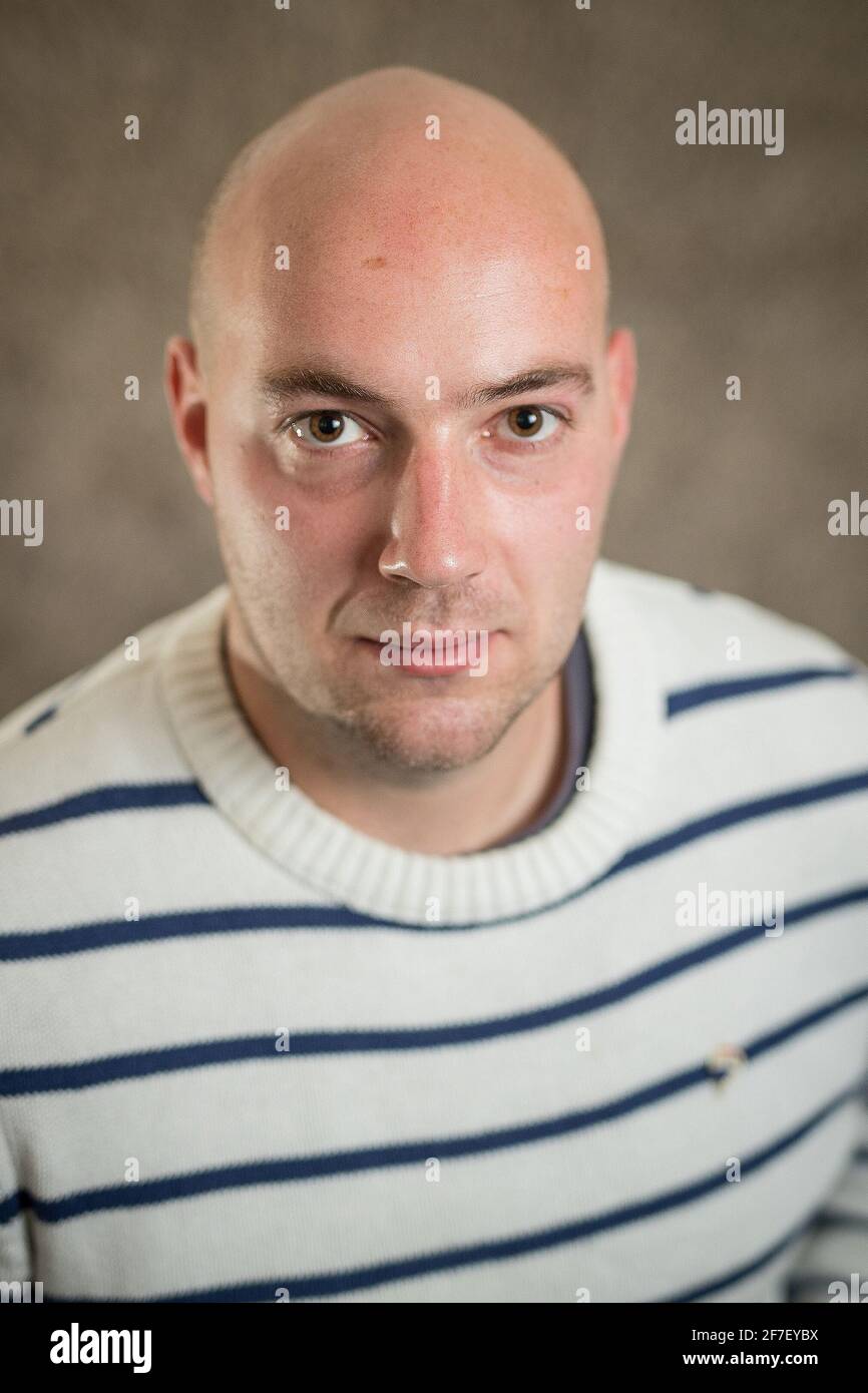 Ritratto di un moderno hipster hipster uomo cripto in un maglione a righe su sfondo grigio. Ritratto informale di giovane uomo d'affari Foto Stock