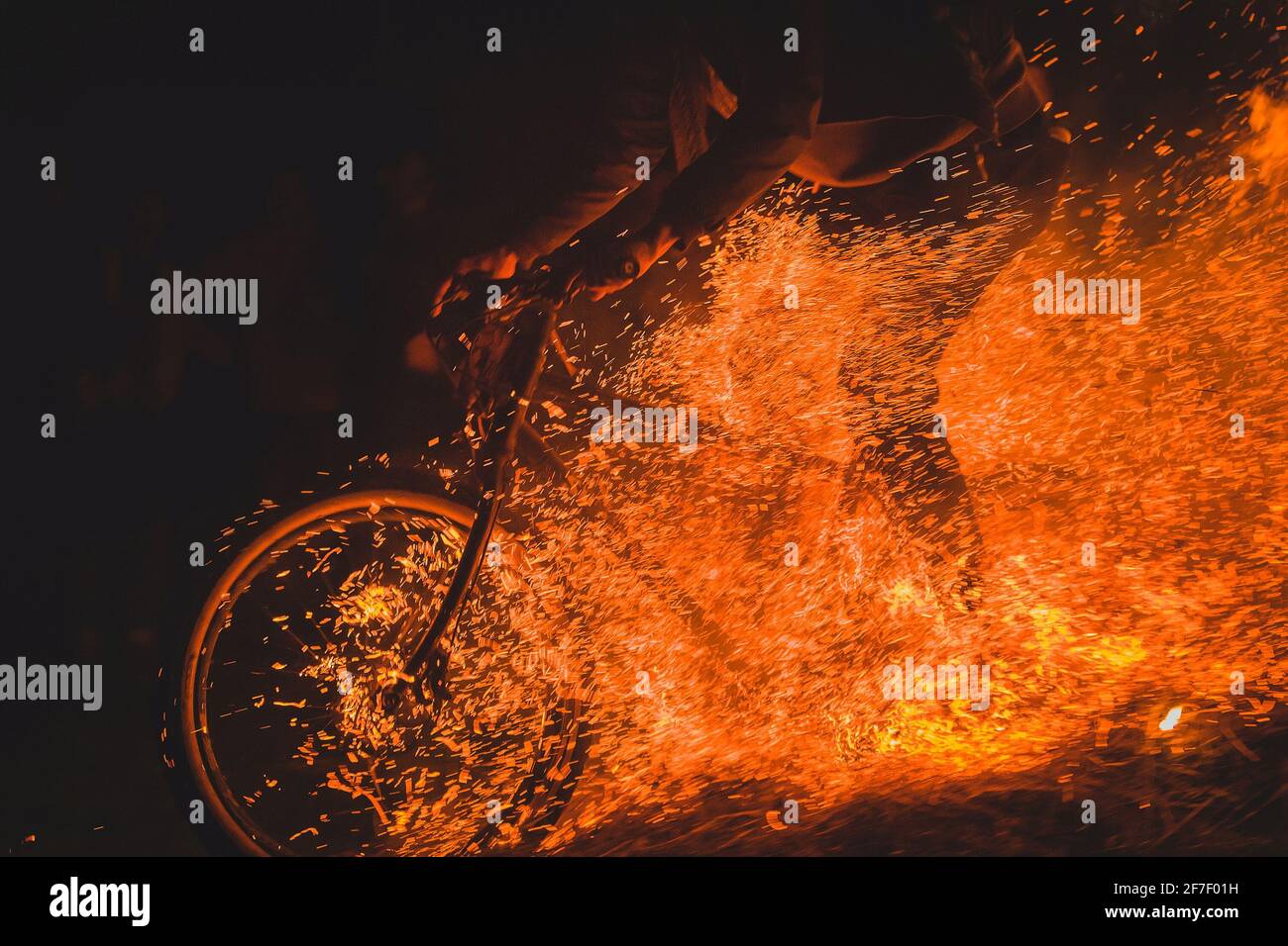 Ciclista completamente pazzesca su una mountain bike a cavallo tra falò, scintille e fiamme che sfrecciano oltre il biker in un evento reale. Biker pericolosamente giocare Foto Stock
