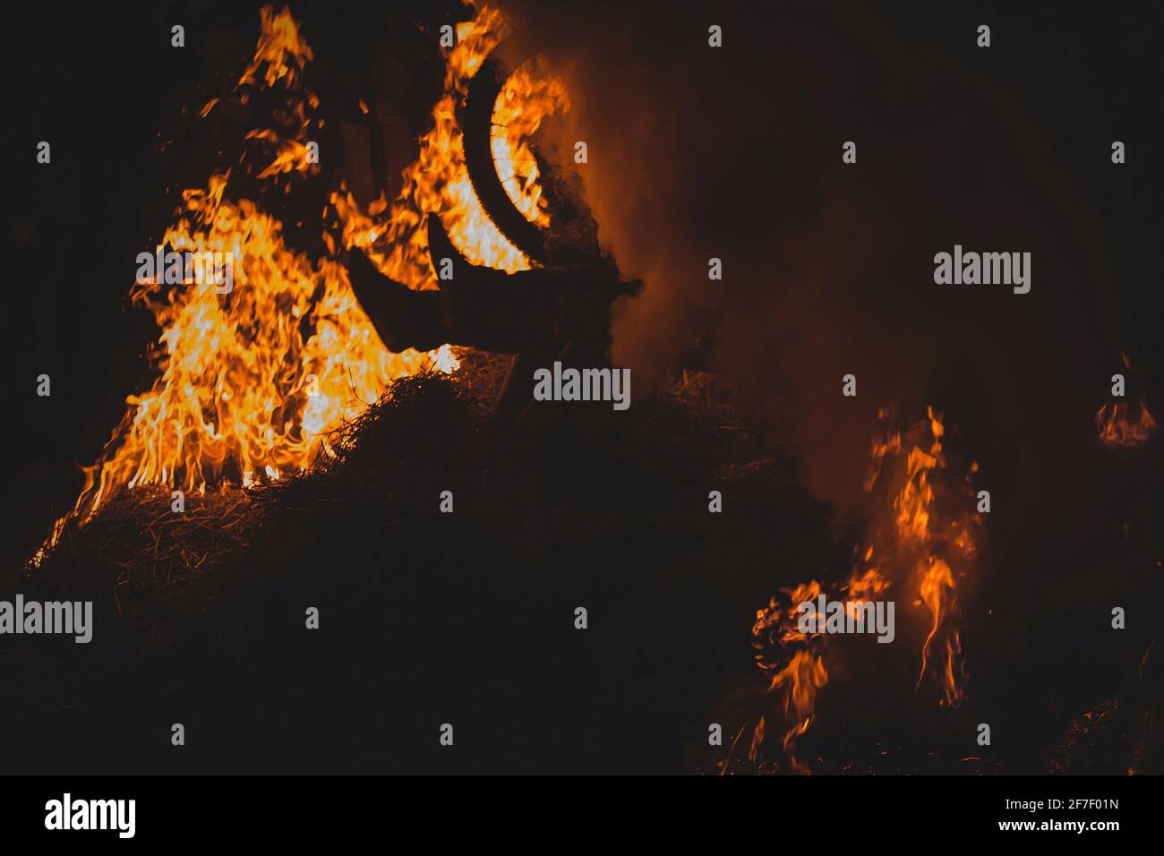 Ciclista completamente pazzesca su una mountain bike a cavallo tra falò, scintille e fiamme che sfrecciano oltre il biker in un evento reale. Biker pericolosamente giocare Foto Stock