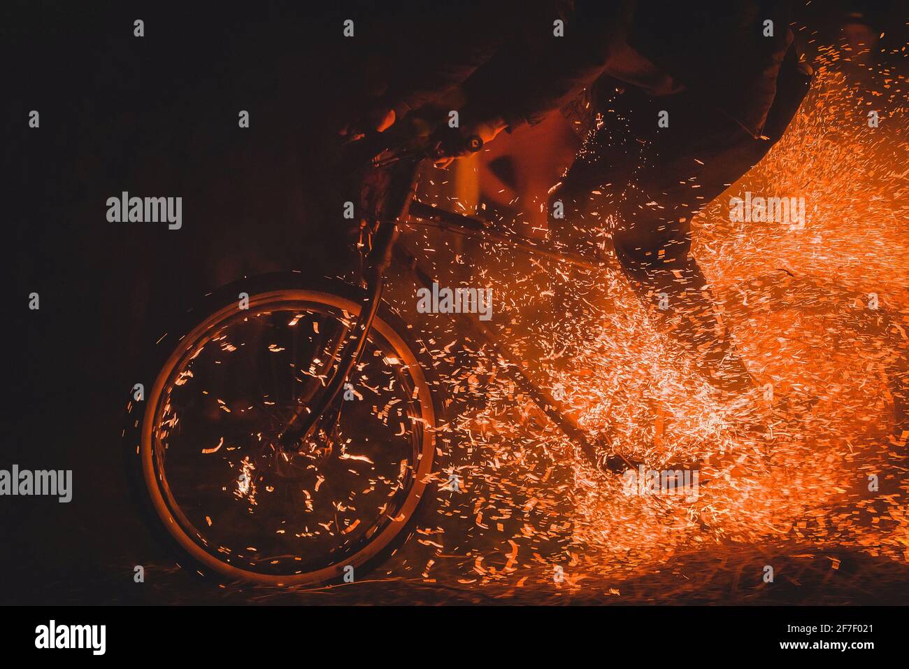 Ciclista completamente pazzesca su una mountain bike a cavallo tra falò, scintille e fiamme che sfrecciano oltre il biker in un evento reale. Biker pericolosamente giocare Foto Stock