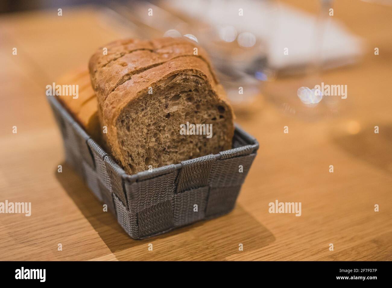 Fette di due diversi tipi di pane in un cesto di tessuto grigio su un tavolo di legno. Servendo con fantasia le fette di pane in profondità di campo poco profonda, concentratevi sul pane Foto Stock
