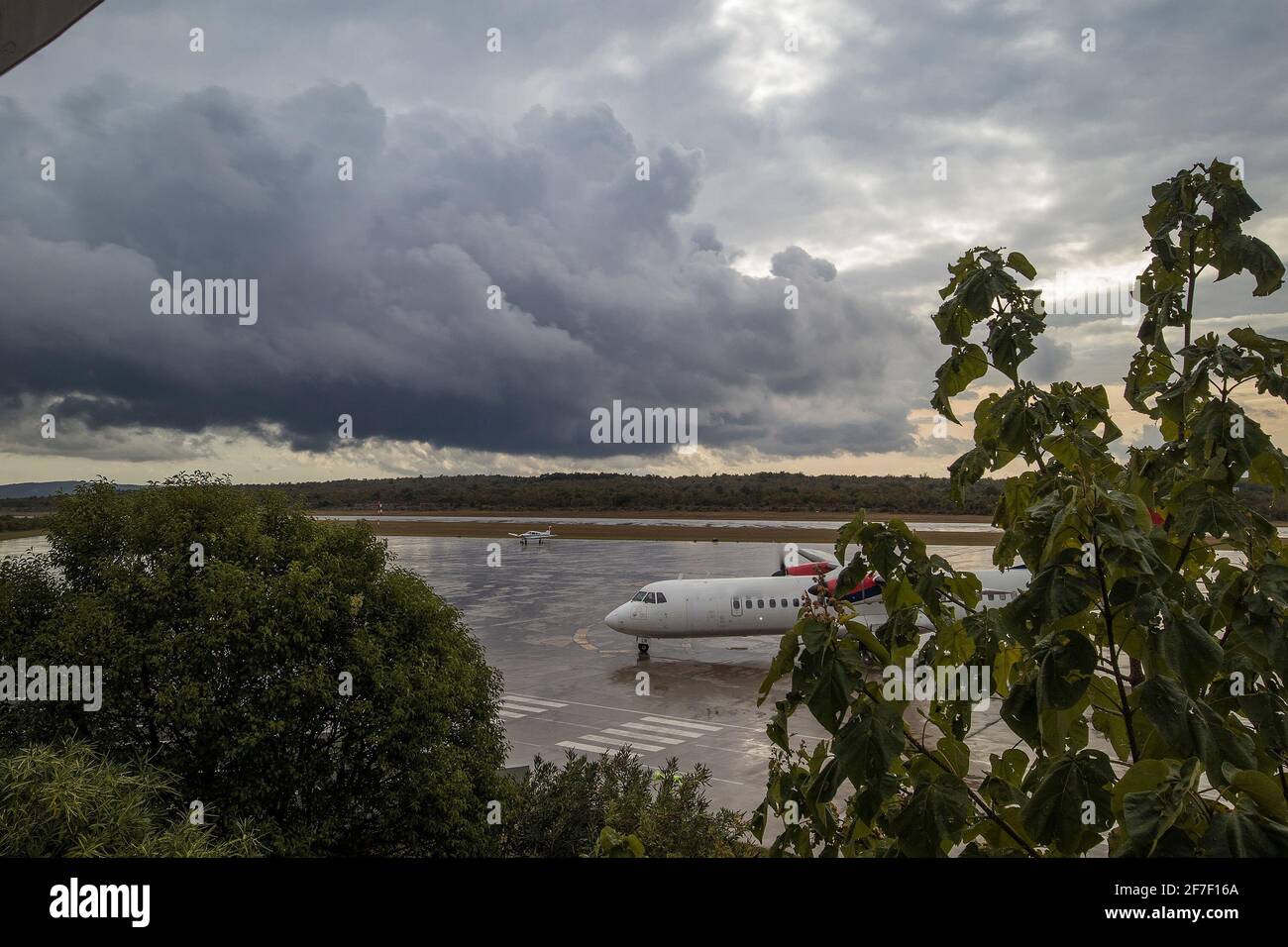 Aereo Propeller che poggia sul grembiule dell'aeroporto internazionale di Rijeka sull'isola di Krk, Croazia, mentre una tempesta si avvicina al campo aereo. Foto Stock