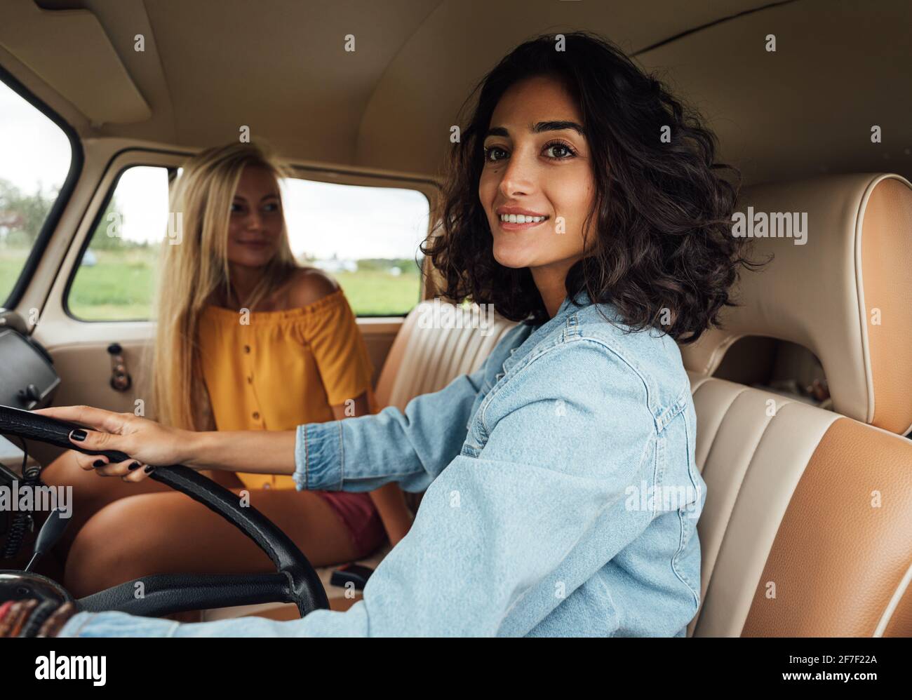 Donna sorridente che guarda fuori dal finestrino dell'auto mentre guida un furgone. Donne amici Foto Stock