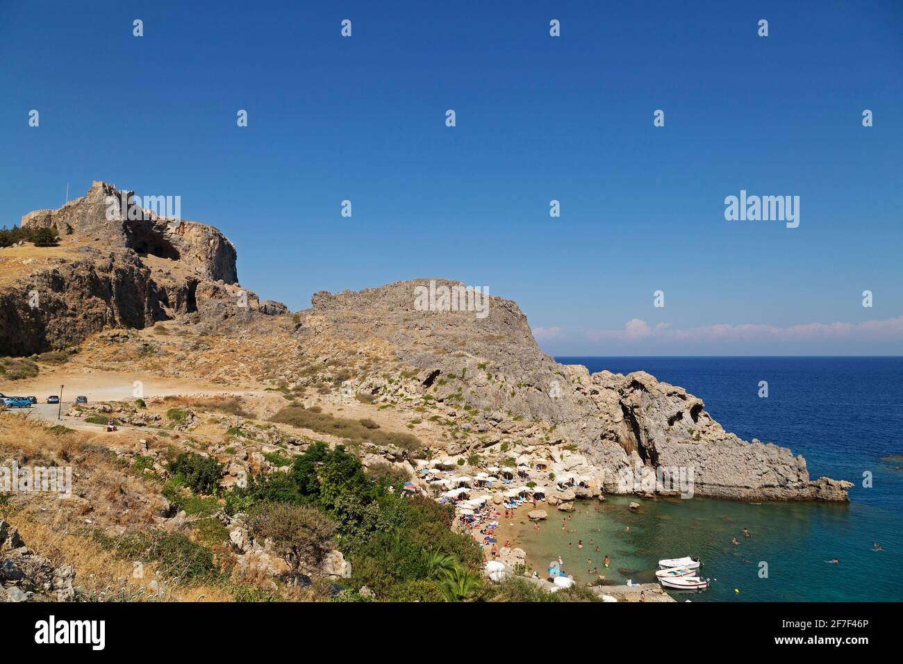 L'Acropoli di Lindian si affaccia sulla baia di San Paolo a Lindos, a Rodi, in Grecia. L'antico monumento si erge sotto un cielo azzurro limpido. Foto Stock