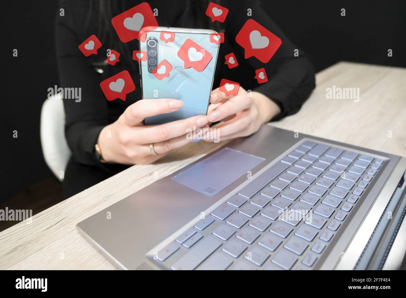 Primo piano di una donna che tiene il telefono cellulare con il cuore rosso come simboli. Concetto di social media. Foto Stock
